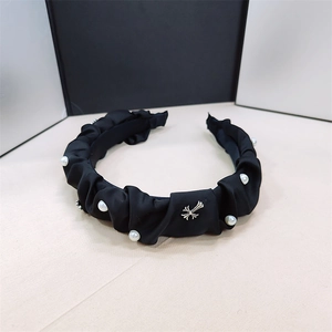 Detail of black pleated satin headband with white pearls and silver cross charm
