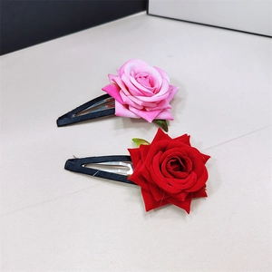 Dettaglio di fermagli per capelli a rosa in tessuto rosso e rosa con base in metallo