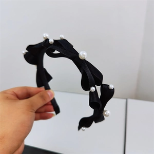 Detail of elegant black satin bow headband decorated with white imitation pearls