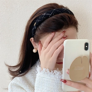 Close-up of black and white tweed headband with gold metal charm detail on side