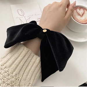 Elegant black velvet bow scrunchie with golden metal charm for hair and wrist styling