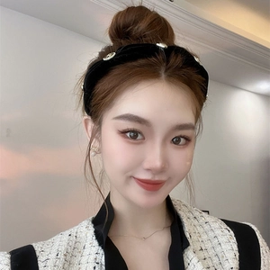 Elegant black velvet headband with gold buttons worn by a model in tweed jacket