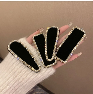 Détail de quatre barrettes en velours noir avec chaînes dorées, perles et strass brillants