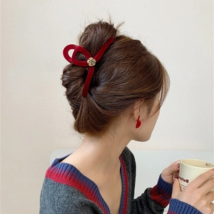 Detailed side view of a large burgundy velvet hair claw clip with golden camellia on hair