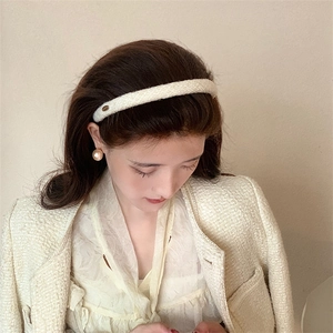 Detail view of white tweed headband with elegant pearls and classic woven texture