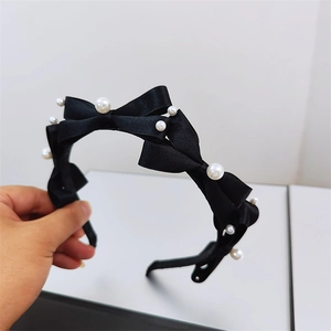 Elegant black satin headband with decorative white faux pearls and a layered bow design
