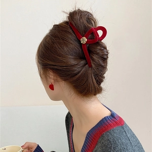 Detailed view of a dark red velvet claw clip with a gold rose on a woman's hair