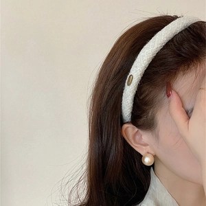 Elegant white tweed headband paired with a large champagne pearl earring on a model