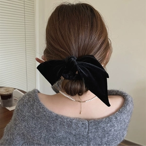 Close-up of a large black velvet bow hair scrunchie styled on an elegant low hair bun