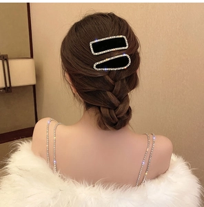 Détail de deux barrettes en velours noir avec bordure en strass sur cheveux tressés