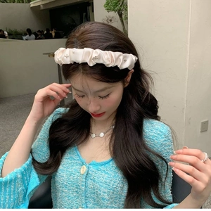 Pink satin pleated headband with pearls and metal accents worn by a model in soft light