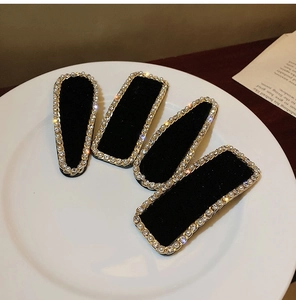 Barrettes en velours noir avec perles et strass posées sur une assiette blanche