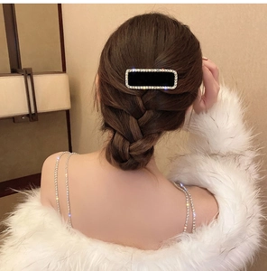 Détail d'une élégante pince à cheveux en velours noir avec cristaux sur une tresse