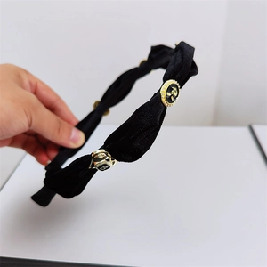 Detail of black velvet headband with vintage enamel flower and pearl ornaments
