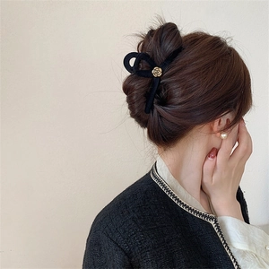 Elegant black velvet hair claw clip with golden camellia flower and bow design