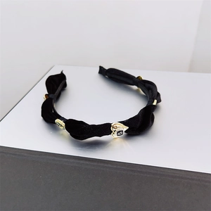 Detailed macro view of black velvet twisted headband with vintage golden charms