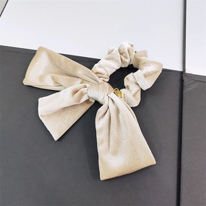 Detail of champagne velvet bow scrunchie with soft texture and golden charm