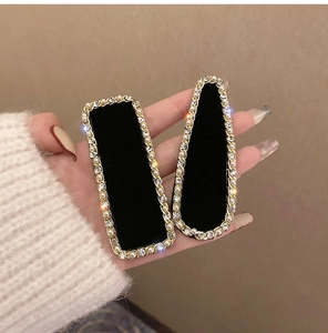 Détail de pinces à cheveux en velours noir avec perles et strass sur socle doré