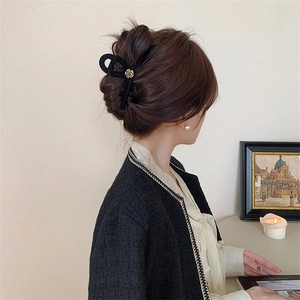 Elegant black velvet hair claw clip with golden rose decoration on model hair