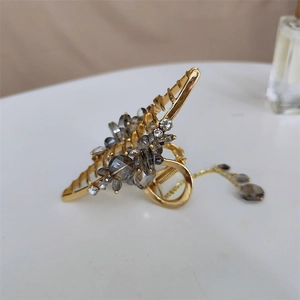 Détail de la pince à cheveux dorée ornée de cristaux gris et d'élégants glands pendants