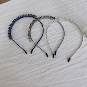 Close-up of beaded hairbands in navy blue, tawny brown, and clear crystal finishes