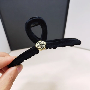 Detailed close-up of velvet hair claw clip with elegant golden metal rose ornament