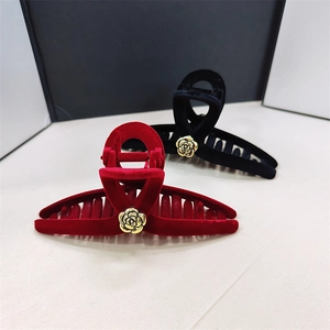 Detailed view of large velvet hair claws with golden camellia flowers in red and black