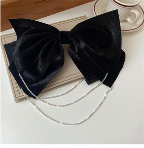 Detail of elegant black velvet bow hair clip with shimmering silver rhinestone chain tassels