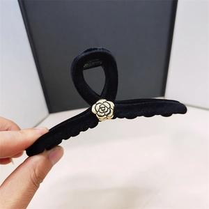 Detail of black velvet hair claw clip with a refined golden metal rose flower center