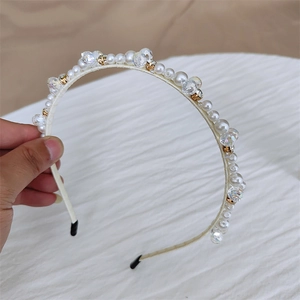 Détail d'un serre-tête fait main orné de perles blanches et de cristaux transparents
