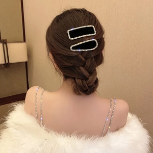 Détail de barrettes en velours noir avec strass portées sur une coiffure tressée élégante