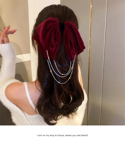 Detail view of burgundy velvet bow hair clip with sparkling rhinestone fringe tassels