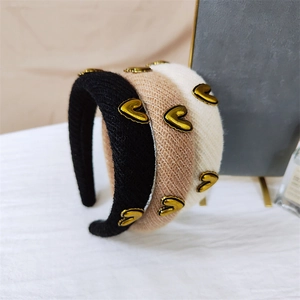 Close-up of knitted headbands with gold heart charms in black, beige, and camel brown colors