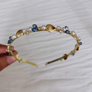 Elegant gold headband with white pearls, blue rhinestones, and metallic sea shell accents