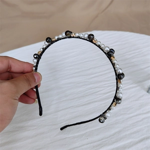 Détail d'un serre-tête avec perles blanches, cristaux noirs et perles dorées sur bandeau fin