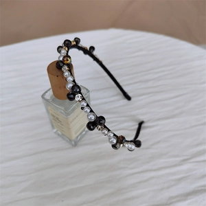 Détail d'un serre-tête perlé à la main avec perles et cristaux d'ambre sur parfum