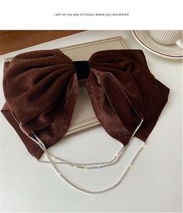 Detail of elegant dark brown velvet bow hair clip with sparkling rhinestone fringe tassels