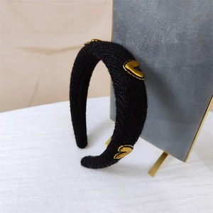 Close-up of black knitted headband featuring three 3D golden metal heart charms