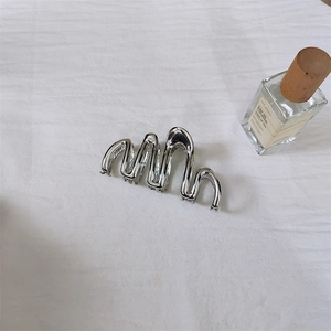Vista dettagliata della grande clip per capelli in metallo argento con design ondulato