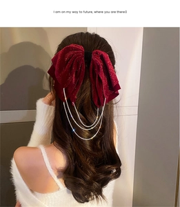 Detail of red velvet bow hair clip with sparkling rhinestone tassels on hair