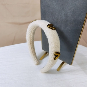 Knitted headband with gold hearts on a padded ivory fabric displayed on a velvet stand