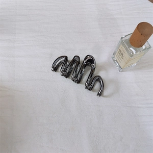 Molletta per capelli in metallo grigio canna di fucile con design a onde su sfondo bianco