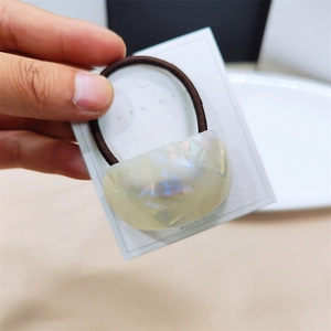 Macro detail of iridescent acetate hair tie with high-elastic brown band on display card