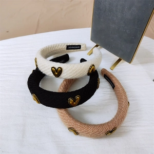 Detailed view of knitted headbands in black, white, and pink with golden heart accents