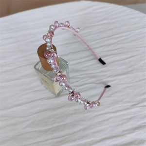 Gros plan d'un serre-tête rose avec perles et cristaux sur un flacon en verre