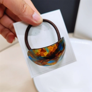 Close-up of semi-circular acetate hair tie with amber texture on white card