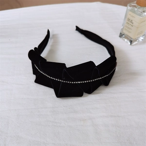 Detailed macro view of black velvet pleated headband with elegant crystal chain inlay