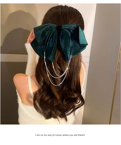 Detail of green velvet bow hair clip featuring sparkling rhinestone tassel chains in hair