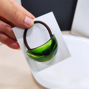 Detail of green iridescent ponytail clip hair ring with high-stretch brown elastic band