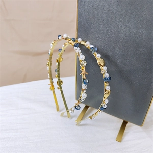 Detail of gold starfish and shell charms with white pearls on a thin metal headband